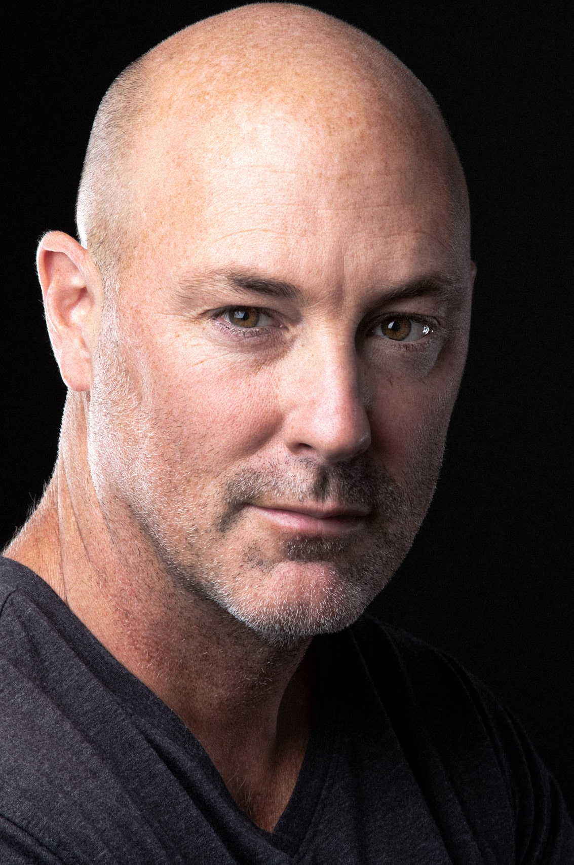 Color headshot of a handsome rugged bald man with a great smile